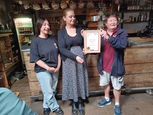 Three people in a bar with a framed certificate